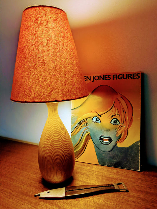 Danish wooden Mid 20th Century table lamp with orange shade on a table next to a book