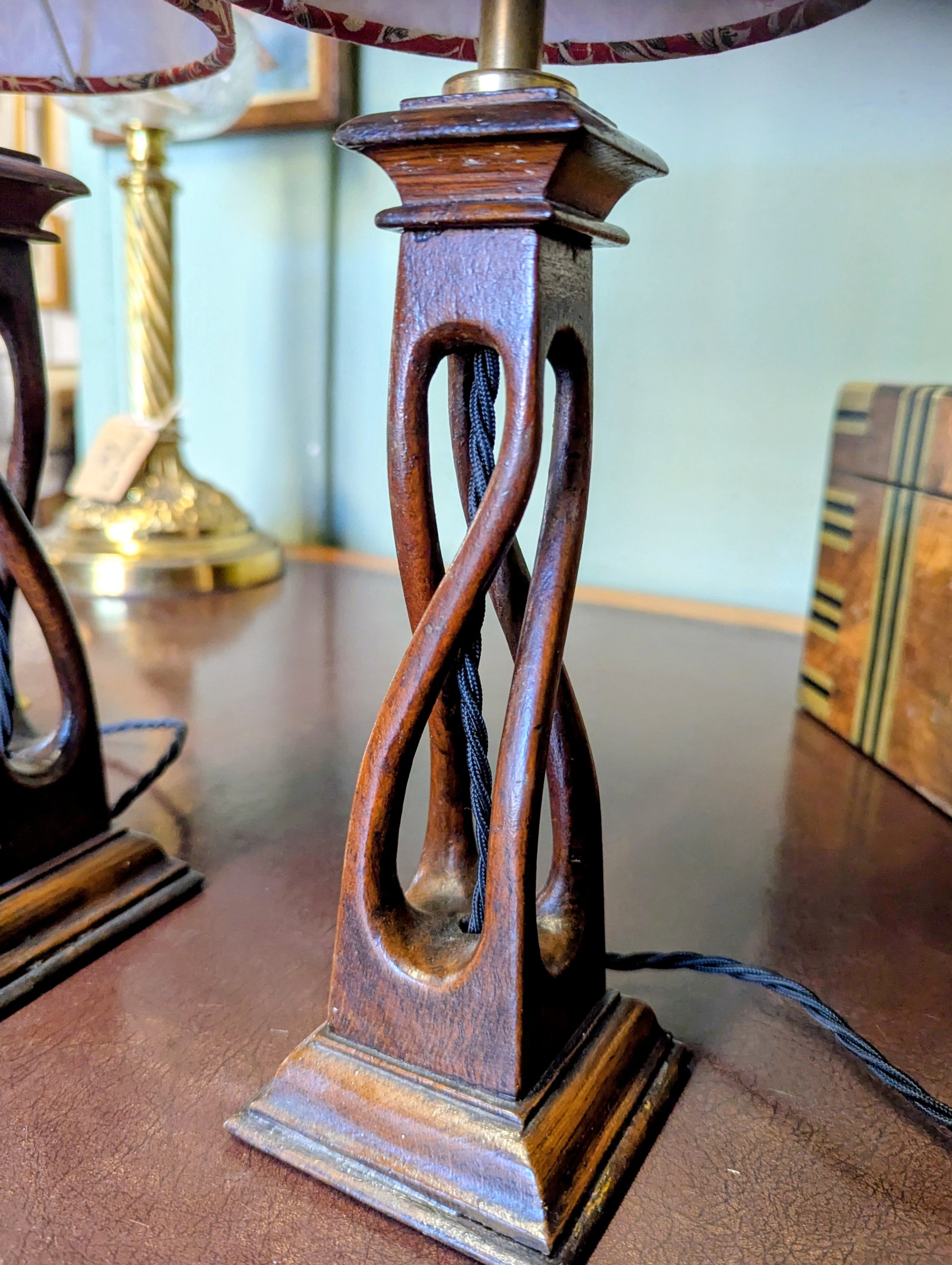 Two arts & crafts movement table lamps with red and white william morris patterned shades on a wooden surface.