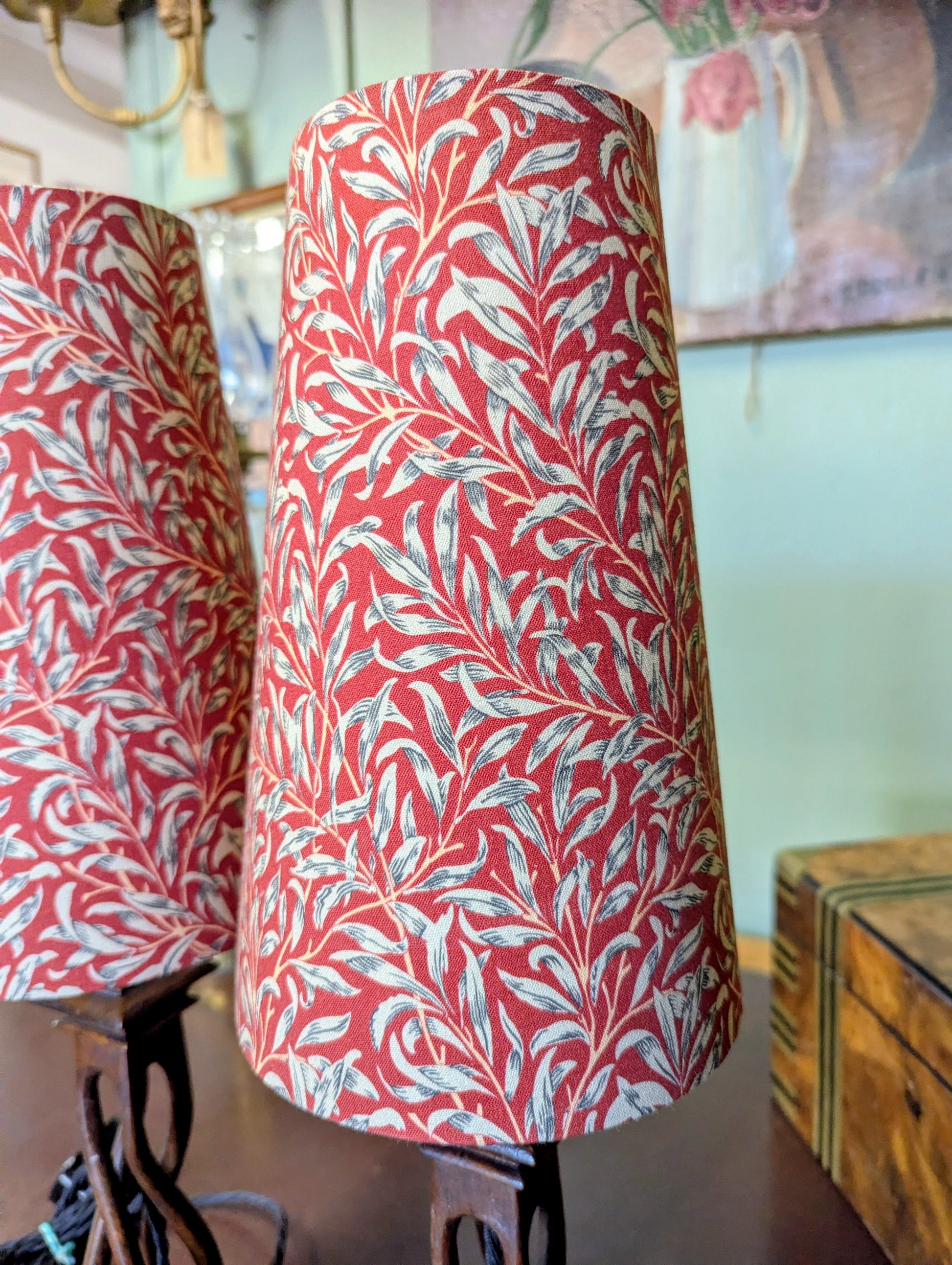 Red and white william morris patterned lampshades on a stand with a blurred background