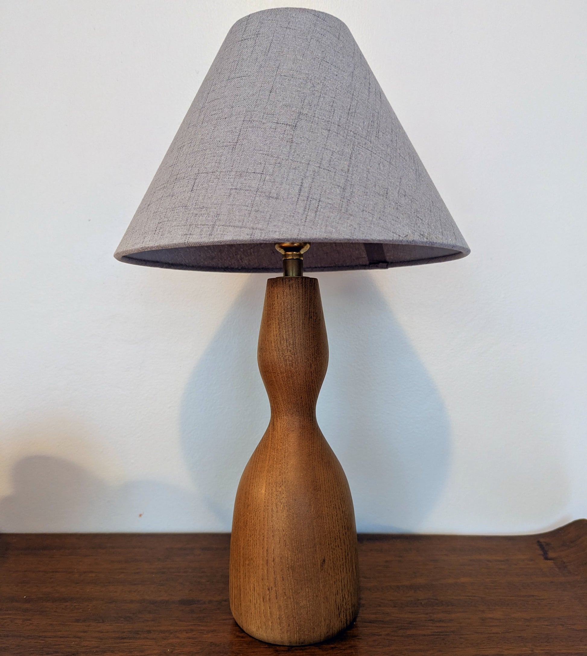 Wooden Danish Mid 20th Century table lamp with a gray lampshade on a wood surface.