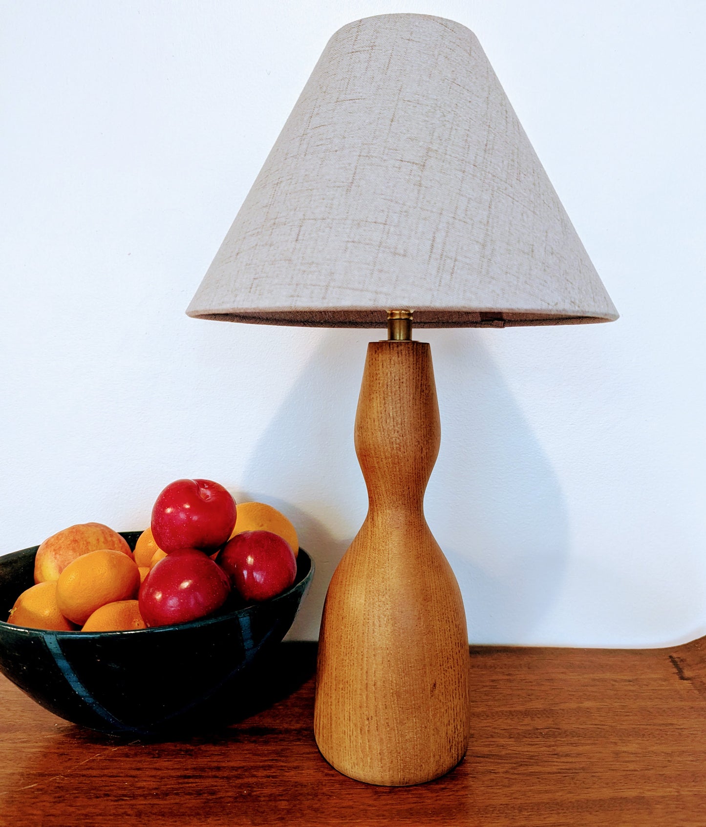 Wooden Danish Mid 20th Century table lamp with a gray lampshade on a wood surface with a bowl of fruit