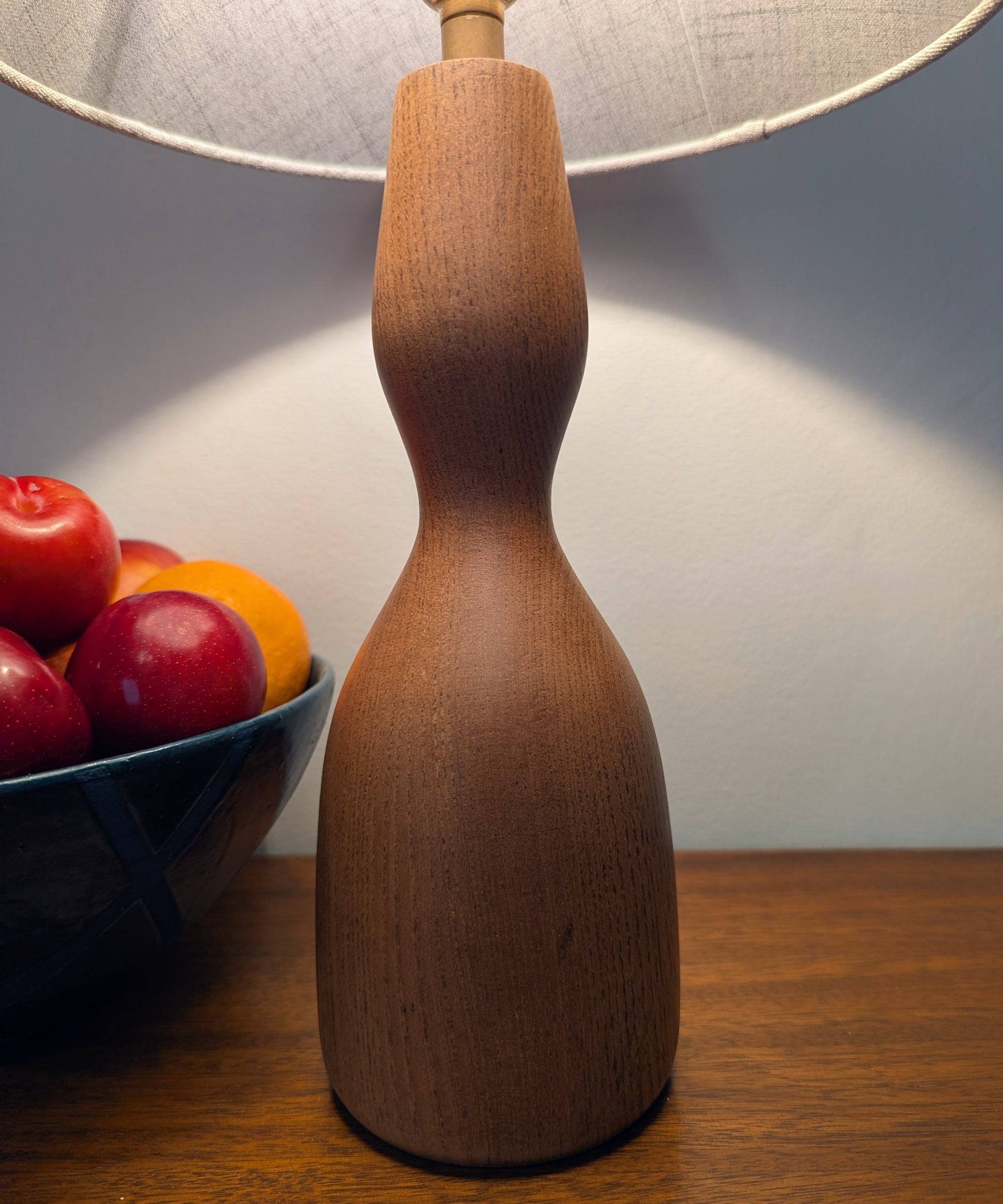 Wooden danish table lamp with a bowl of plums on a wooden surface