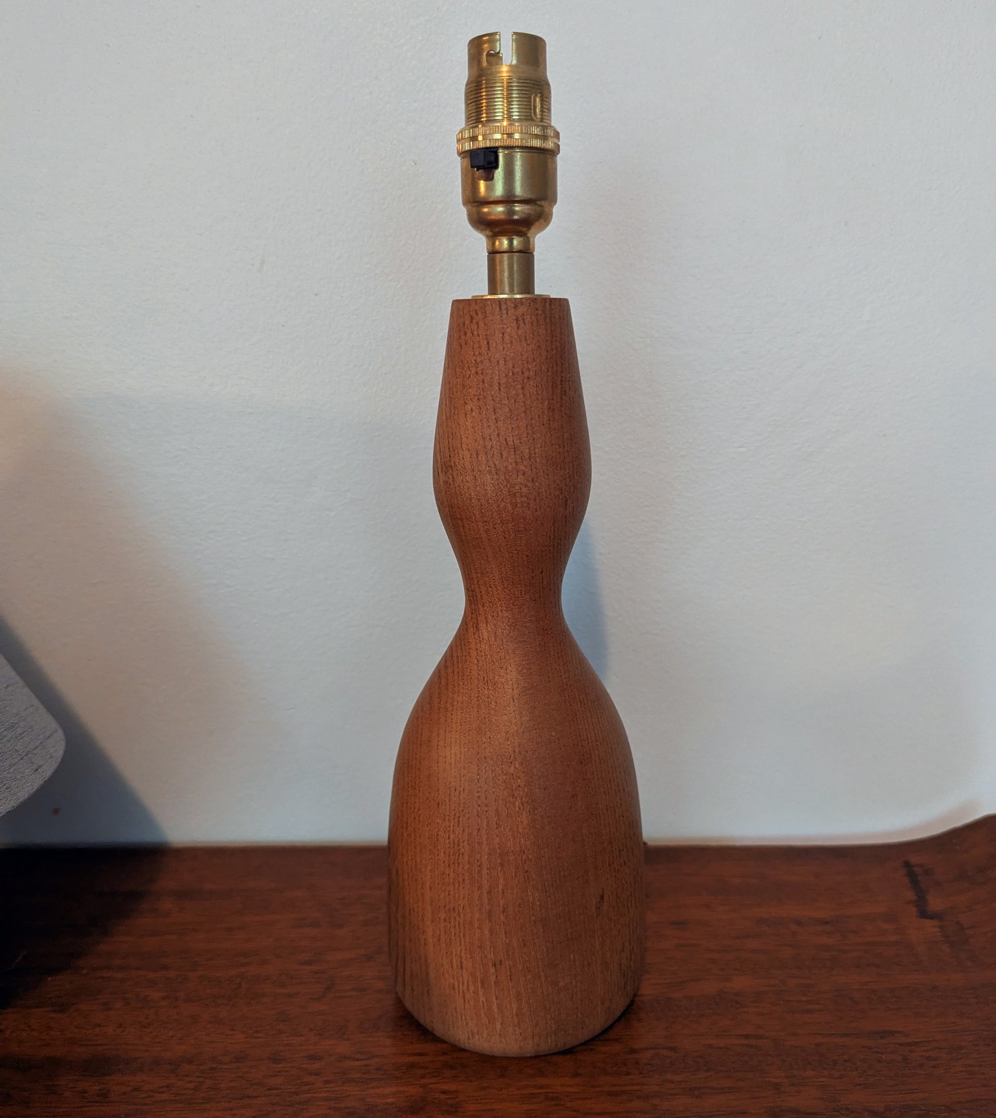 Wooden mid 20th Century Danish table lamp base with brass fitting on a wooden surface