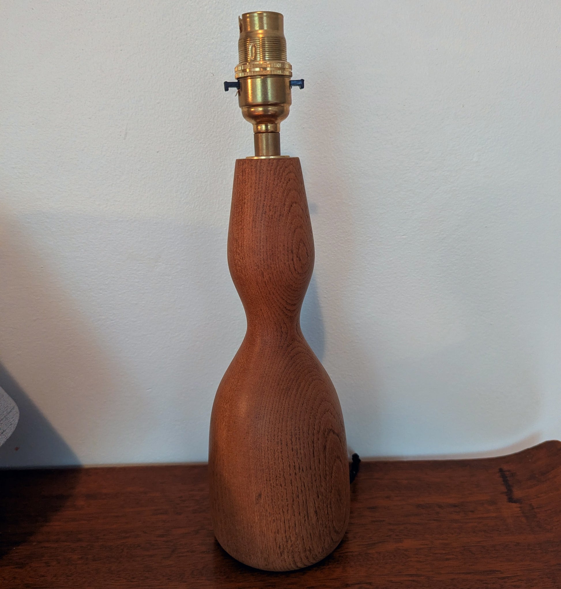 Wooden mid 20th Century Danish table lamp base with brass fitting on a wooden surface