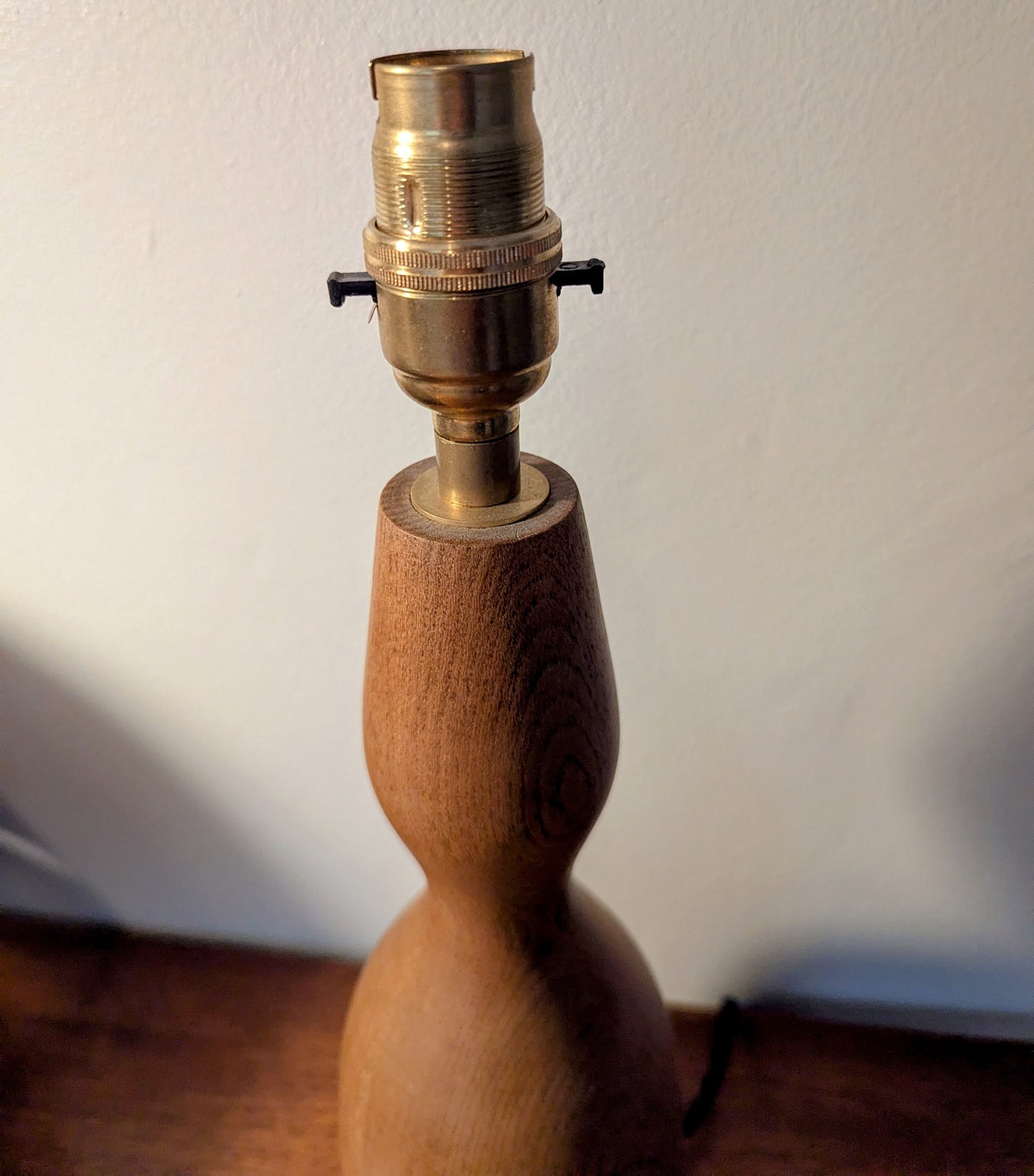 Wooden mid 20th Century Danish table lamp base with brass fitting on a wooden surface